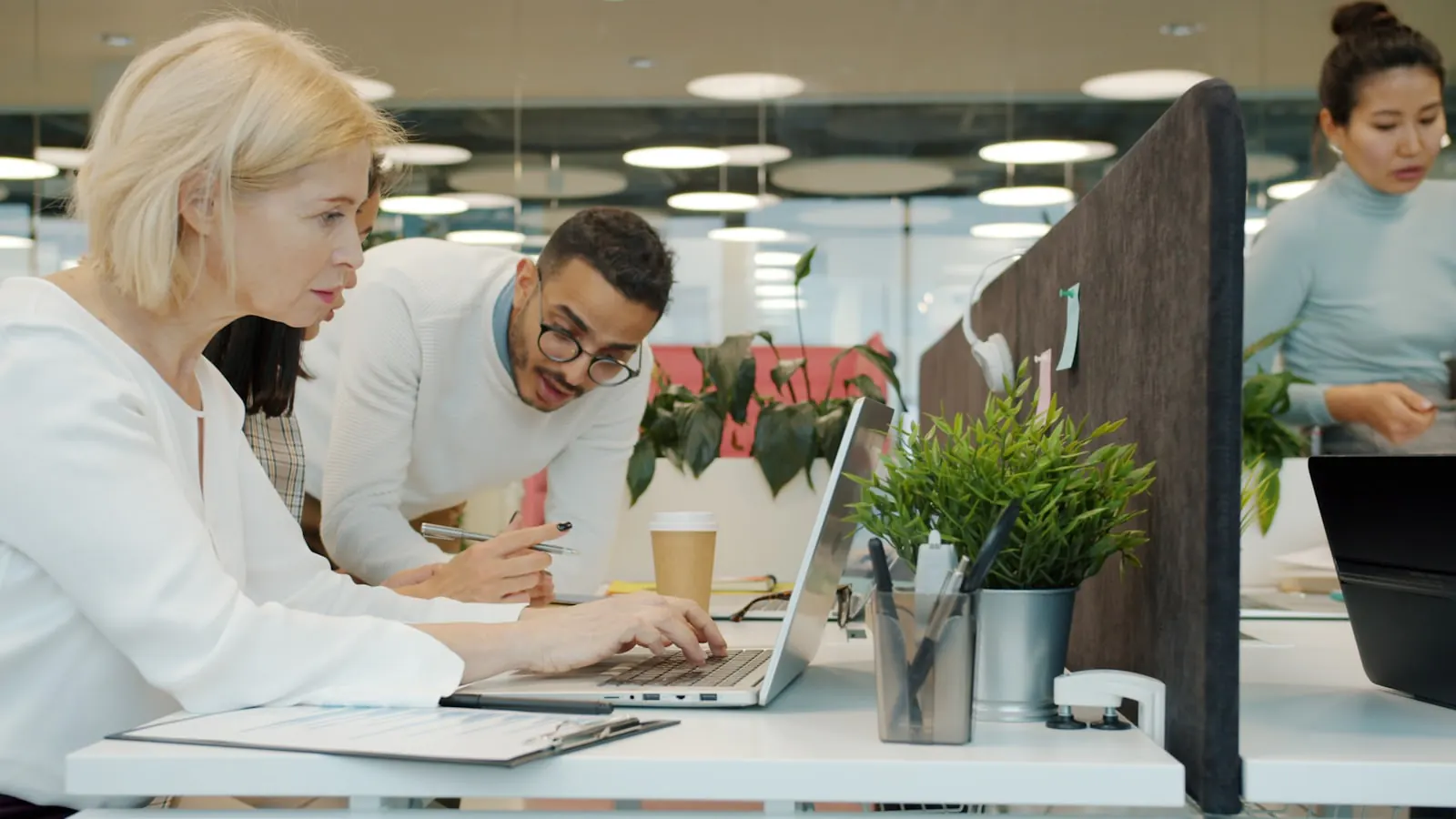 A diverse team collaborating over a laptop in a bright modern office.