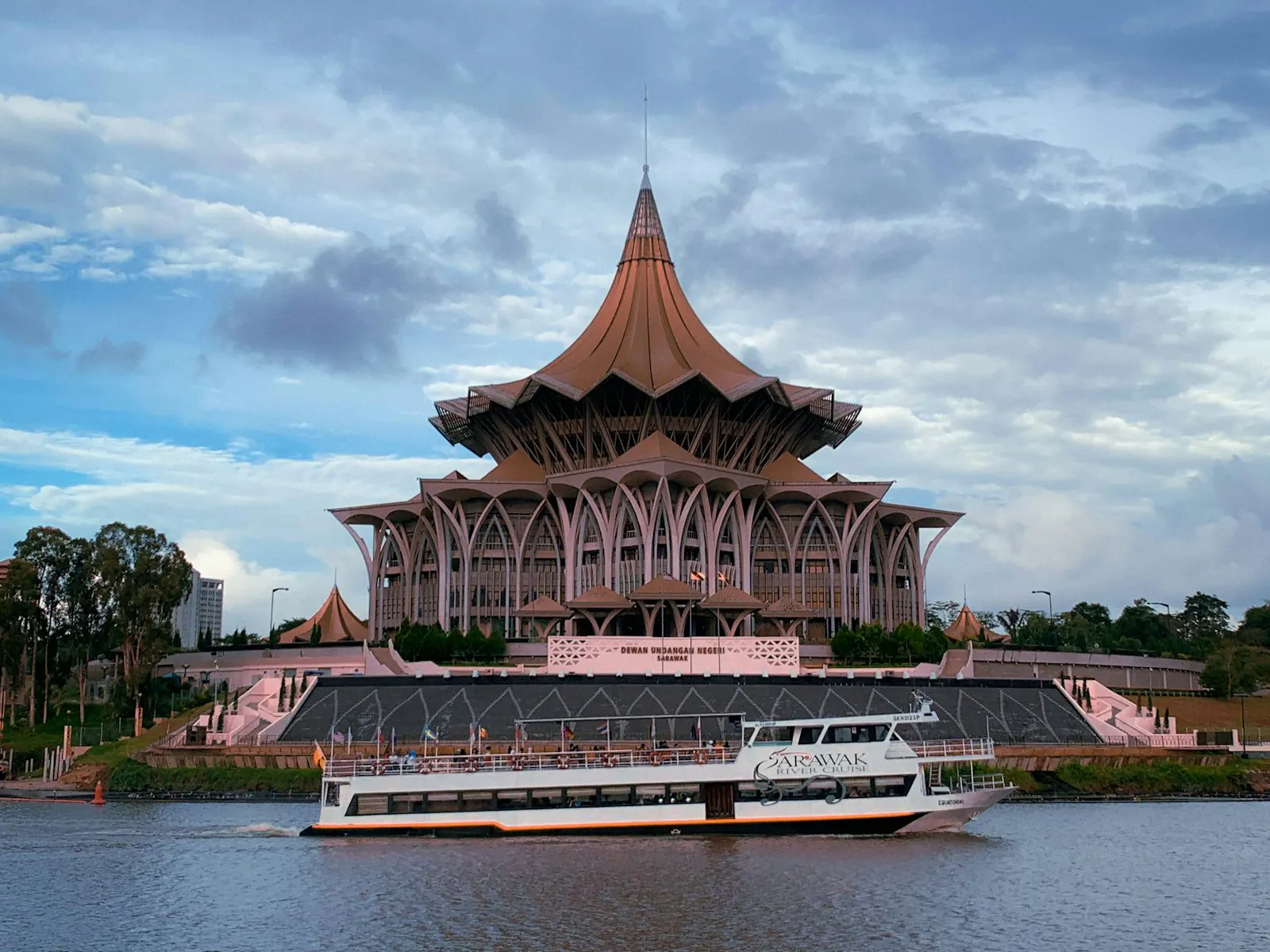 The Sarawak State Legislative Assembly and a river cruise boat on the Kuching waterfront.